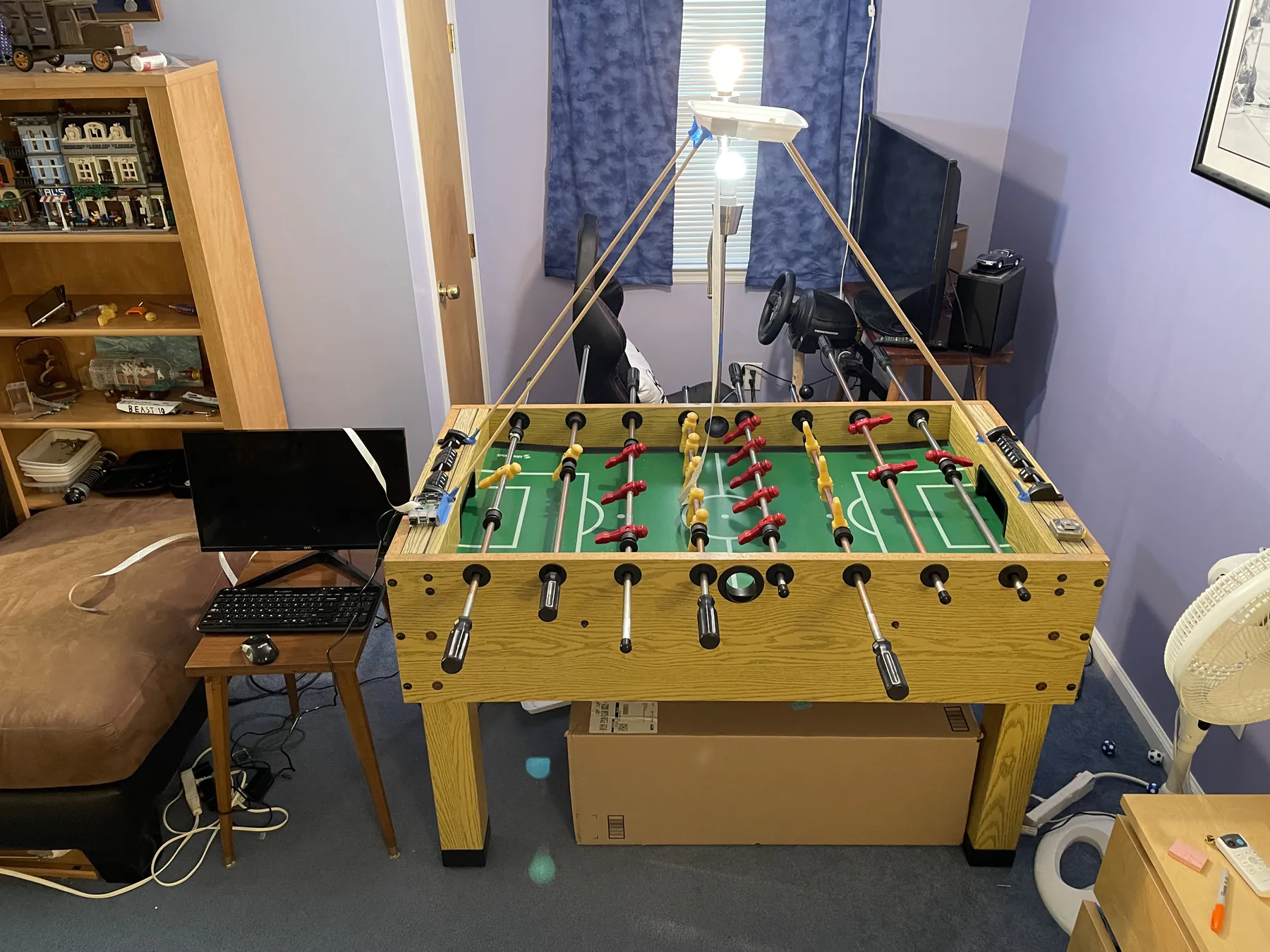The first setup: the reassembled table in the bedroom with the improvised dowel-and-takeout-container camera mount suspended above it and a monitor and keyboard on a side table
